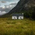 Einsames weißes Cottage in den schottischen Highlands unter einem stürmischen Himmel